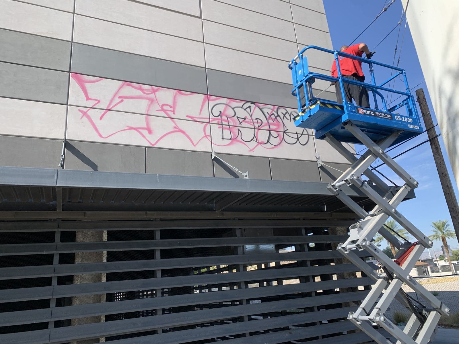 Tony on a lift removing graffiti from a building